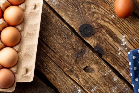 Brown chicken eggs packaged on a wooden background, cooking at home with copyspace top view