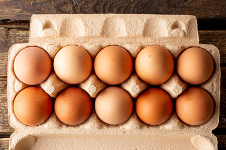Brown chicken eggs packaged on a wooden background, cooking at home top view
