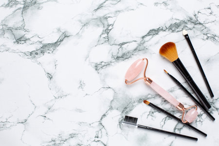 Pink Gua Sha massage tool on a marble background, close-up. Rose Quartz jade roller. Facial skin care at home, anti-aging and lifting therapy top viewの写真素材