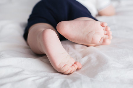 Feet of baby boy on bed. Legs on a white background side viewの写真素材