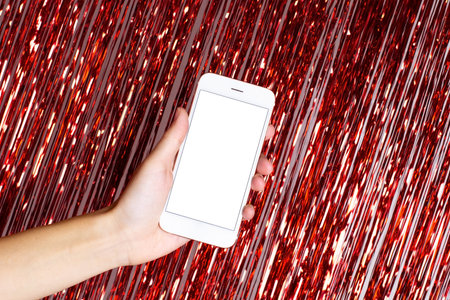 Christmas red lights and bokeh. Smart phone in hand with isolated screen for mockup, app or web site design presentation side viewの写真素材