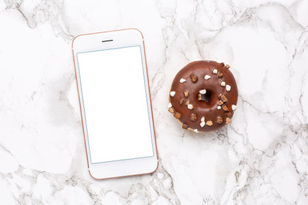 Mobile phone and sweet donut on a marble background flat lay, technology and sweet food top viewの写真素材