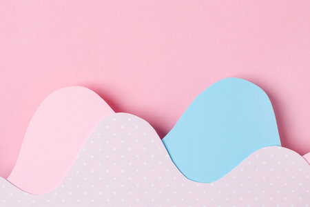 Different layers of abstract paper pink and blue waves on pastel background with copyspace top view