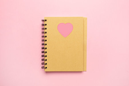 Spiral notepad with pink heart on pink paper background, minimalism note and valentines day