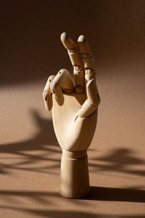 A hand of wood doll make fingers to touch, direct, move on brown background at the studio with dark...
