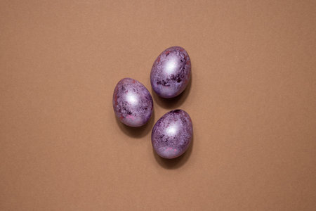 Glitter Easter eggs in pink purple colors on beige background. Easter holiday creative concept...