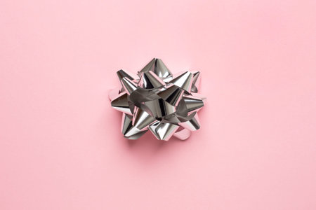 Decorative bow Close up photo in minimal style Silver gift bow on pink background Template for...