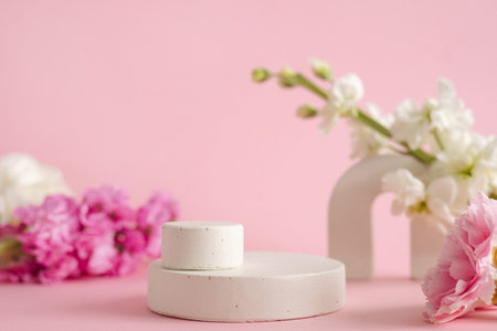 Empty podium for presentation of cosmetic products. Pastel flowers on pink background side viewの写真素材