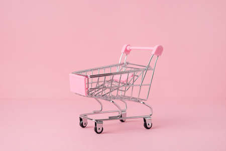 Small shopping market trolley on a pink background, copy space, shopping concept side viewの写真素材