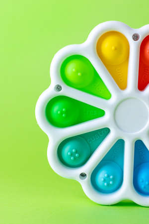 Presses with a finger anti-stress toy pop it on the green background. Colorful silicone poppit toy, bubble fidget, simple-dimpleの写真素材