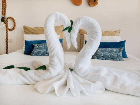 Towel white swans couple kiss heart shape on bed sheet hotel guest room decoration backgroundの写真素材