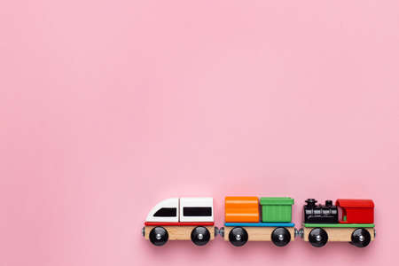 Train children toy, preschool kids game. Locomotive and carriages, wooden colorful blocks construction on pink color backgroundの写真素材