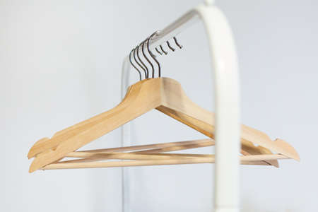 A wooden hanger hangs on a stainless steel rail in a room with white wallsの写真素材