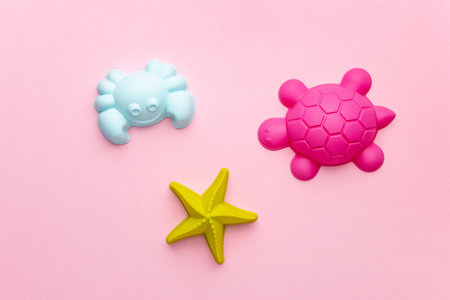 Plastic beach toy pastel color on pink background. The development of fine motor concept. Creativity...