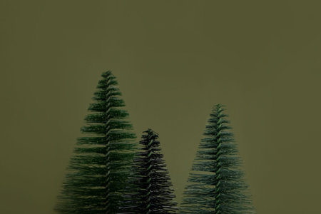 Small decorative green christmas tree on a green background. Christmas card with a place for an...