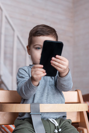 Cute little toddler boy playing with smartphone Healthy baby touching mobile phone with fingers,...