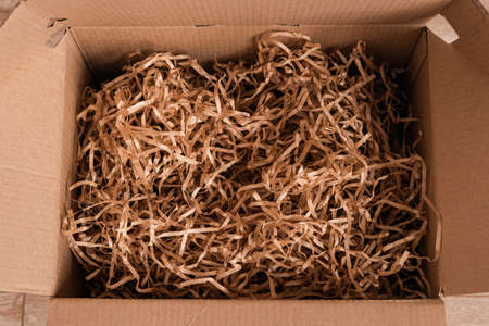 Moving day, box with paper material.Eco material for packaging goods, things, fragile items. Decorative wood shavingsの写真素材