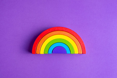 Colorful Waldorf wooden human figure rainbow in a montessori teaching pedagogy on purple background,...