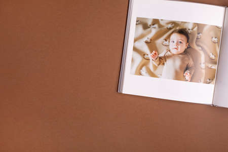 Babys photo book on brown background . Childrens emotional portrait.Cute toddler boyの写真素材
