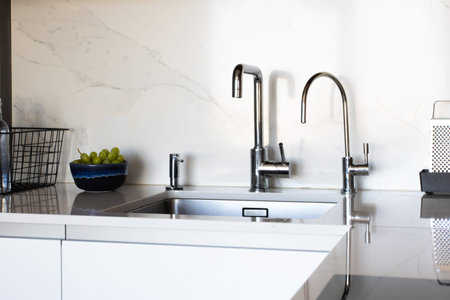 Kitchen brass utensils, chef accessories. Hanging modern kitchen with white marble wall and stone...