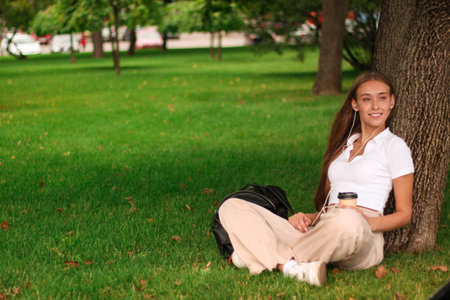 Portrait of a young girl sitting on the grass in the parkの写真素材