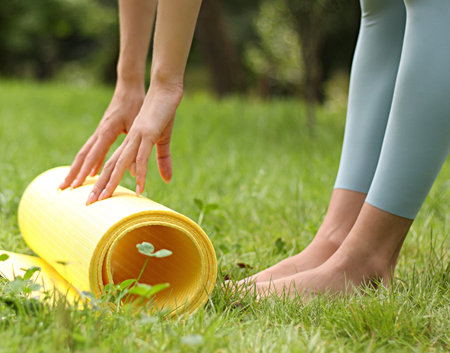 Close up of female hands holding yoga mat on grass in park.の写真素材