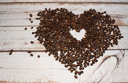 Heart coffee frame made of dark roasted coffee beans on a wooden backgroundの写真素材