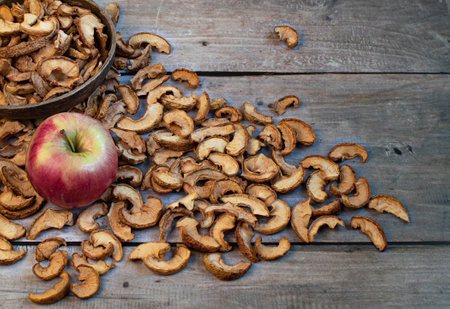 Ripe apple and dried apples in a bowl on wooden background . Harvesting and drying apples. Dried apple slices on the table. Dried fruit chips. Healthy vegan foodの写真素材