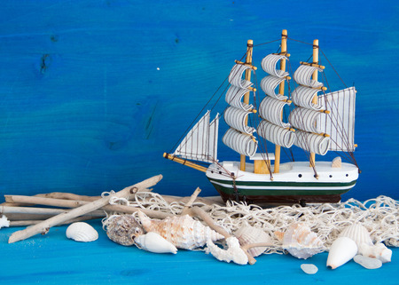 Toy sailboat, weathered wood and seashells on blue woodの写真素材