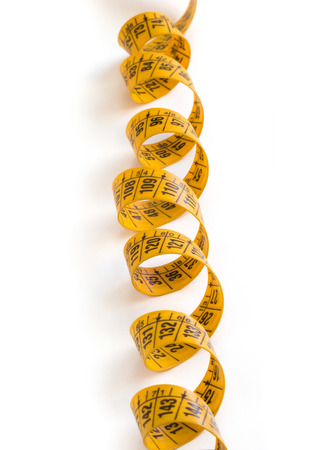 A coiled yellow measuring tape isolated on whiteの写真素材