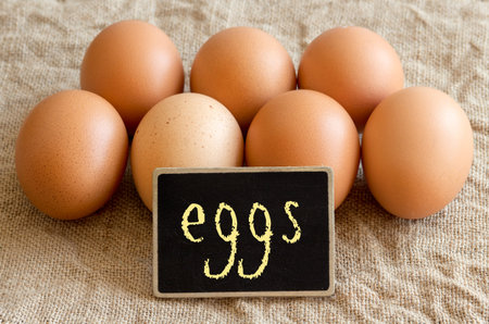 Chicken eggs and small chalkboard on burlap close up