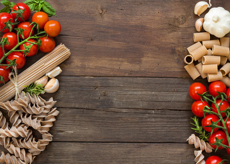 Pasta, garlic, herbs and tomatoes on the wooden tableの写真素材