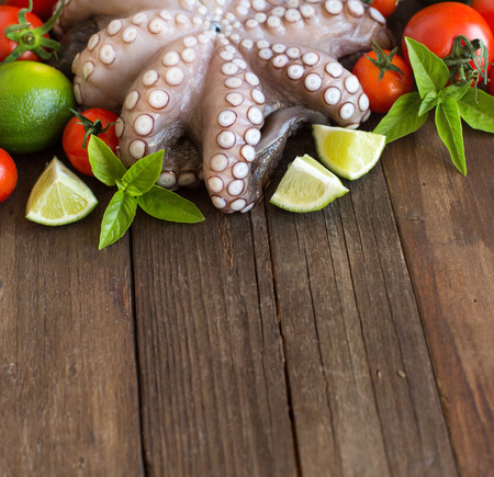 Raw octopus with lime, tomatoes and herbs over wooden backgroundの写真素材
