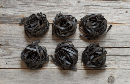 6 Black tagliatelle on an old wooden tableの写真素材