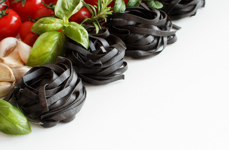 Black Tagliatelle pasta with cherry tomatoes, garlic and herbs on woodの写真素材