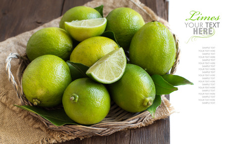 Fresh limes in a basket on a wooden tableの写真素材