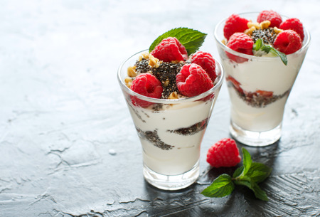 Yogurt with chia seeds, walnuts, mint and raspberries on dark backgroundの写真素材
