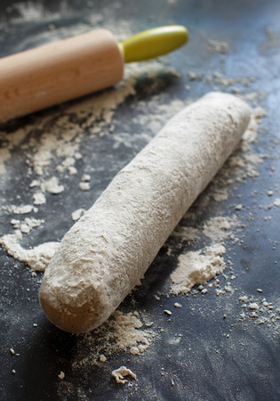 Raw dough with a rolling pin on a dark backgroundの写真素材