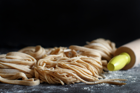 Fresh homemade pasta and rolling pin on a dark backgroundの写真素材