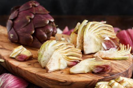 Roman Artichokes on a wooden board with knifeの写真素材