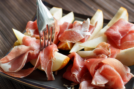 Appetizer with pear and italian parma ham close upの写真素材