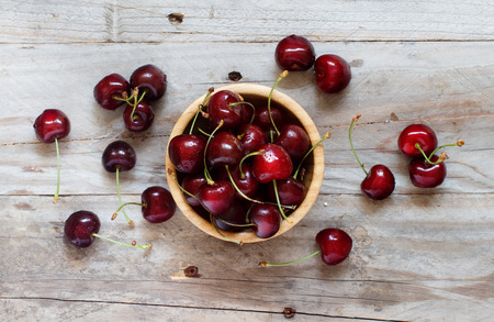 Red cherries in a bowl on a old wooden backgroundの写真素材