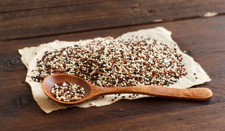 Pile of uncooked mixed red, white and black quinoa  with a spoonの写真素材