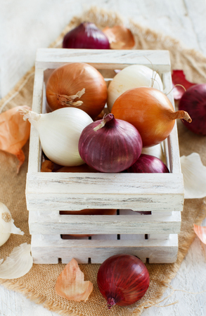 Raw onions in a box on a wooden tableの写真素材