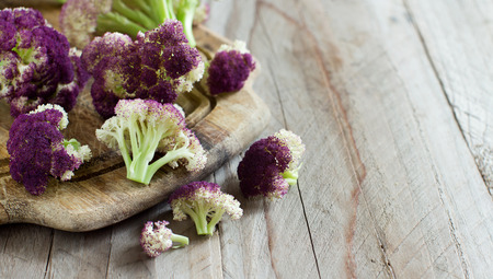 Fresh raw purple cauliflower on a wooden board close upの写真素材