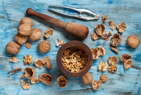 Fresh walnuts with mortar and pestle on a blue wooden table top view