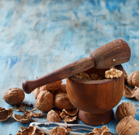 Fresh walnuts with mortar and pestle on a blue wooden table close upの写真素材