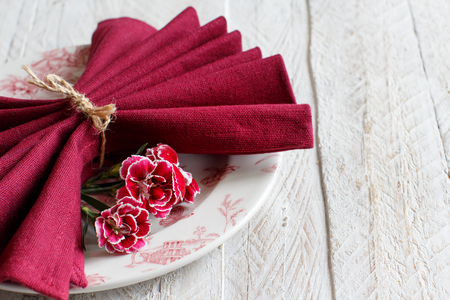 Table setting with carnation flowers and dark red napkinの写真素材