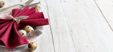 Easter table setting with quail eggs and feathers