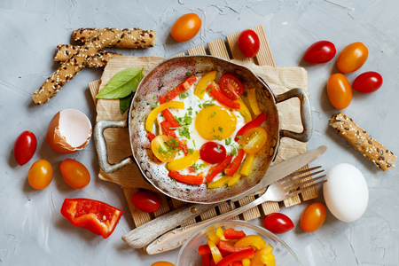 Fried egg with a bell pepper and tomatoes on an old frying pan  top viewの写真素材